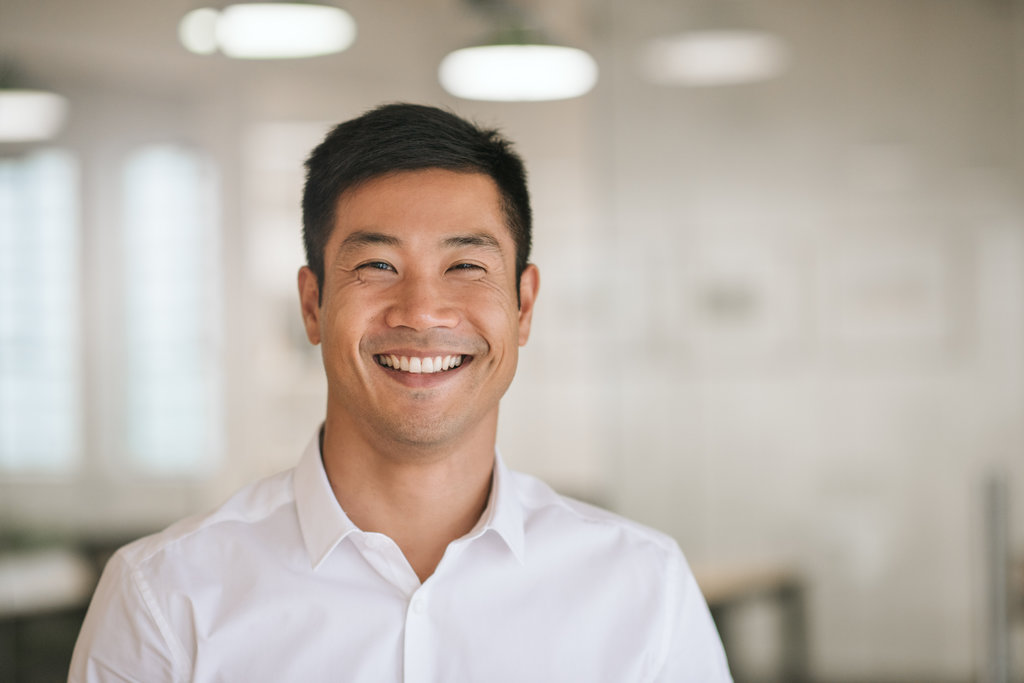 Well dressed young Asian businessman smiling confidently while standing alone in a bright modern office
