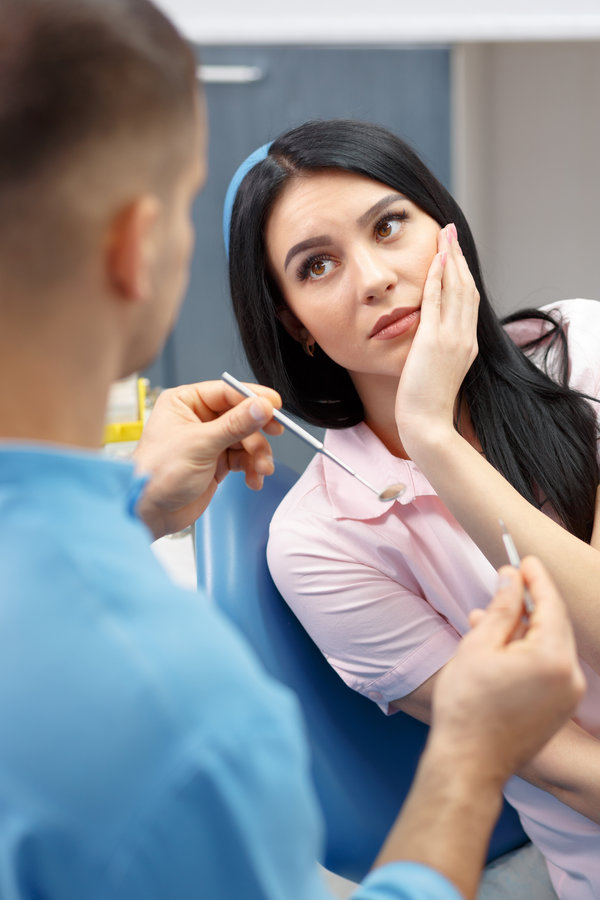 Girl patient goes to the dentist with a toothache in the dental office. Young woman holding the hand of a sick tooth