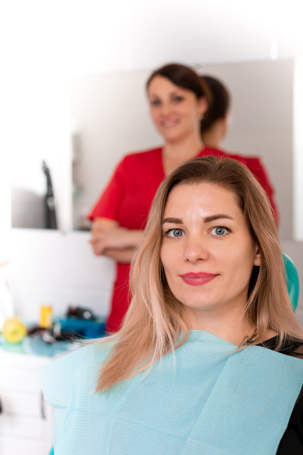 The dentist and her happy patient look at the camera and smile. Reception at the dentist, healthy teeth, happy patient, beautiful teeth