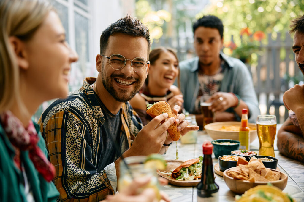 Young cheerful man having lunch with friends in Mexican restaurant.