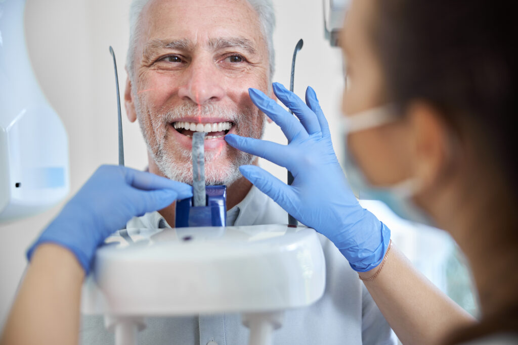 Close-up photo of a skillful dental technician preparing a senior man for a panoramic dental x-ray